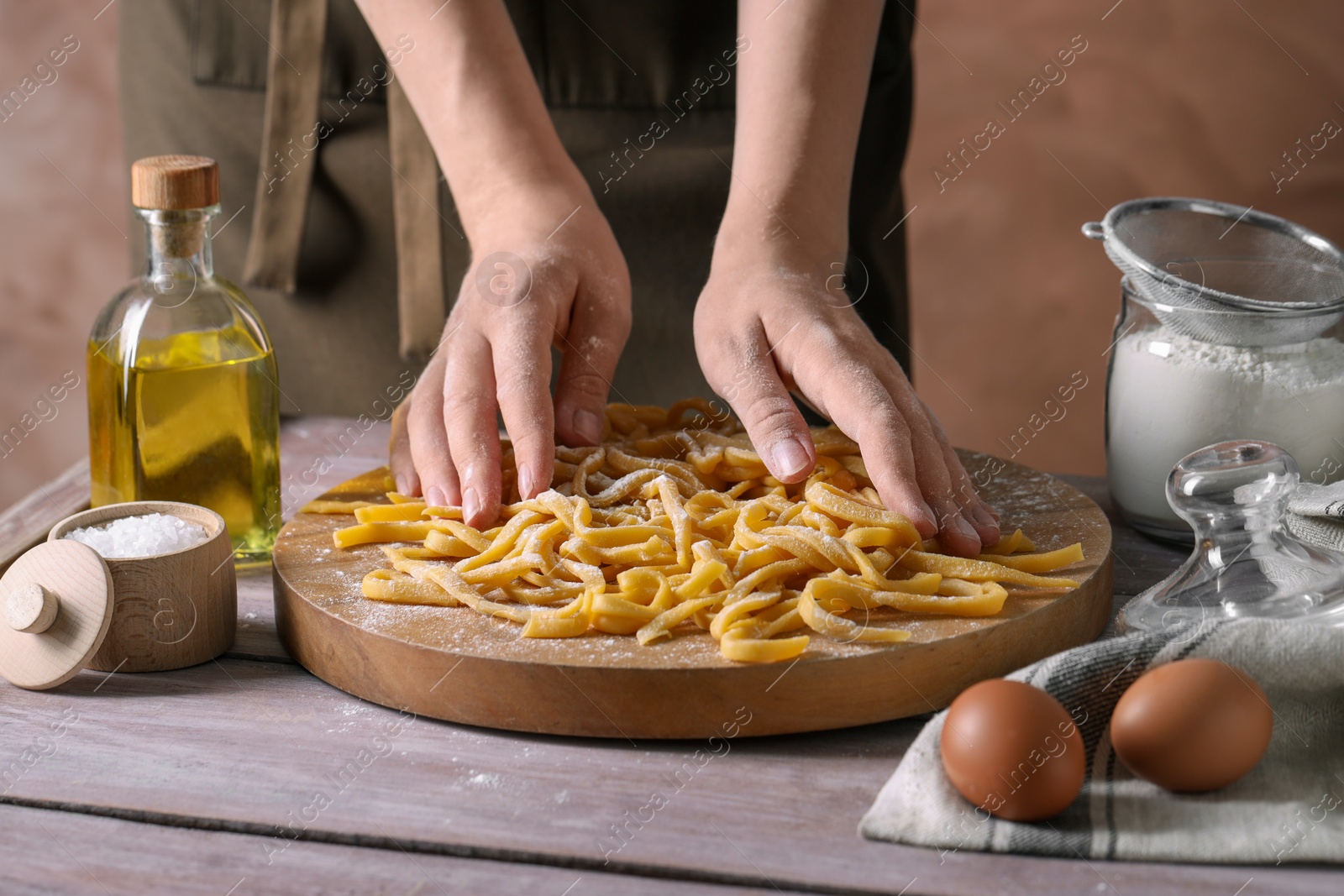 Photo of Woman making homemade pasta at wooden table, closeup