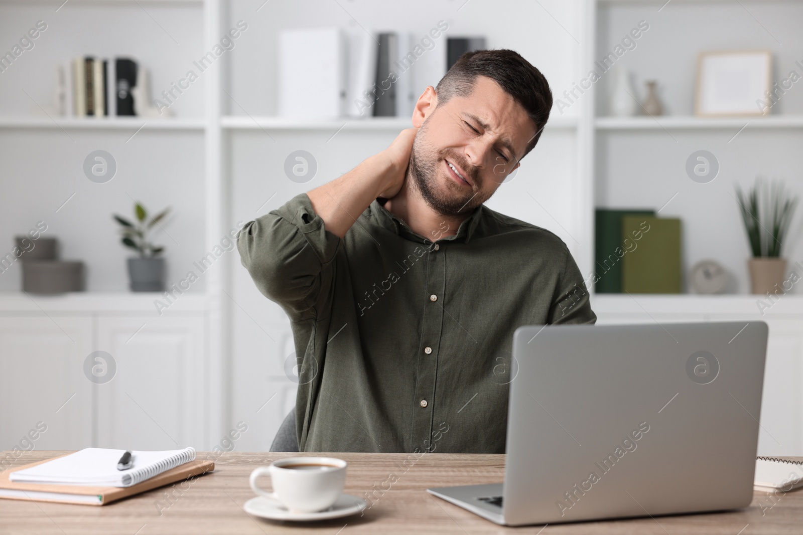 Photo of Man suffering from neck pain in office