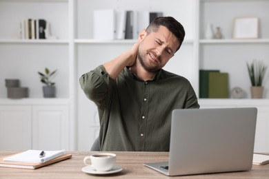 Photo of Man suffering from neck pain in office