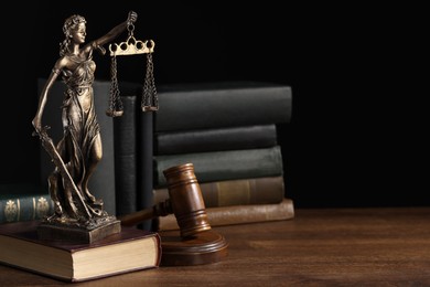 Symbol of fair treatment under law. Statue of Lady Justice near books and gavel on wooden table, space for text.