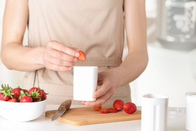 Woman preparing homemade yogurt with strawberry in kitchen. Recipe for multi cooker