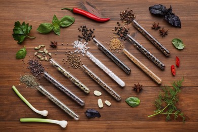 Photo of Flat lay composition with various spices, test tubes and fresh herbs on wooden background