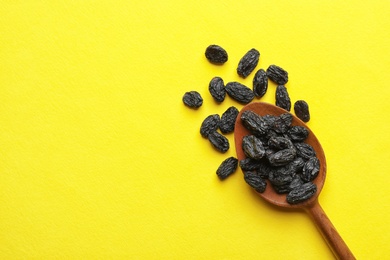 Photo of Spoon with raisins and space for text on color background, top view. Dried fruit as healthy snack