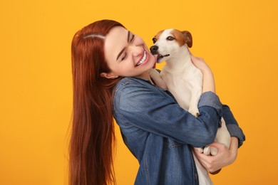 Photo of Happy woman with her cute Jack Russell Terrier dog on orange background
