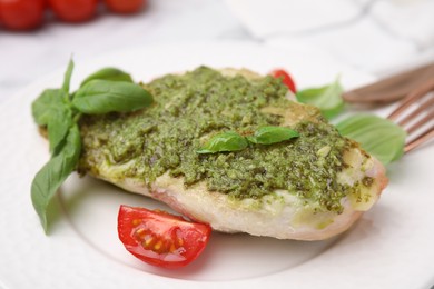 Delicious chicken breast with pesto sauce, tomato and basil on table, closeup