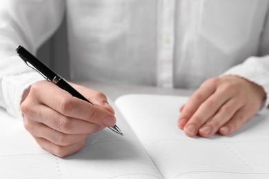 Photo of Woman with pen and notepad at light table, closeup