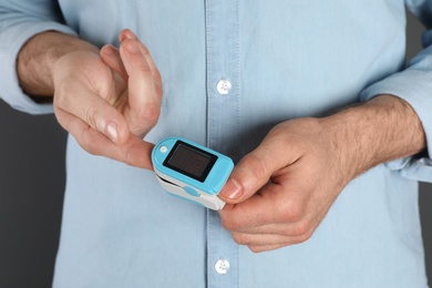 Photo of Young man checking pulse with finger digital medical device, closeup