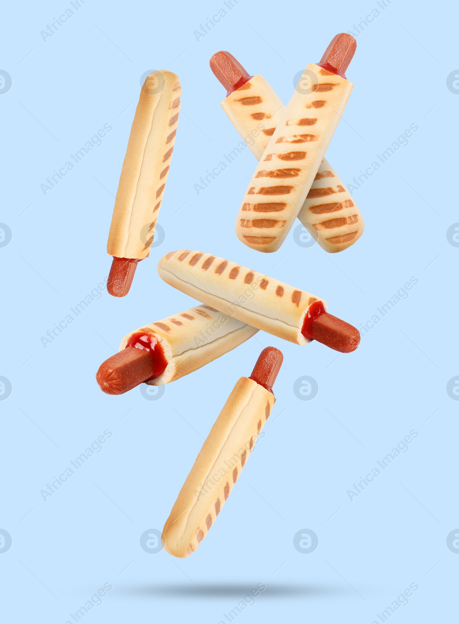 Image of Yummy French hot dogs with grilled buns falling on light blue background