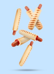 Image of Yummy French hot dogs with grilled buns falling on light blue background