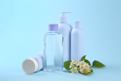 Photo of Baby care products and beautiful flowers on light blue background. Space for text