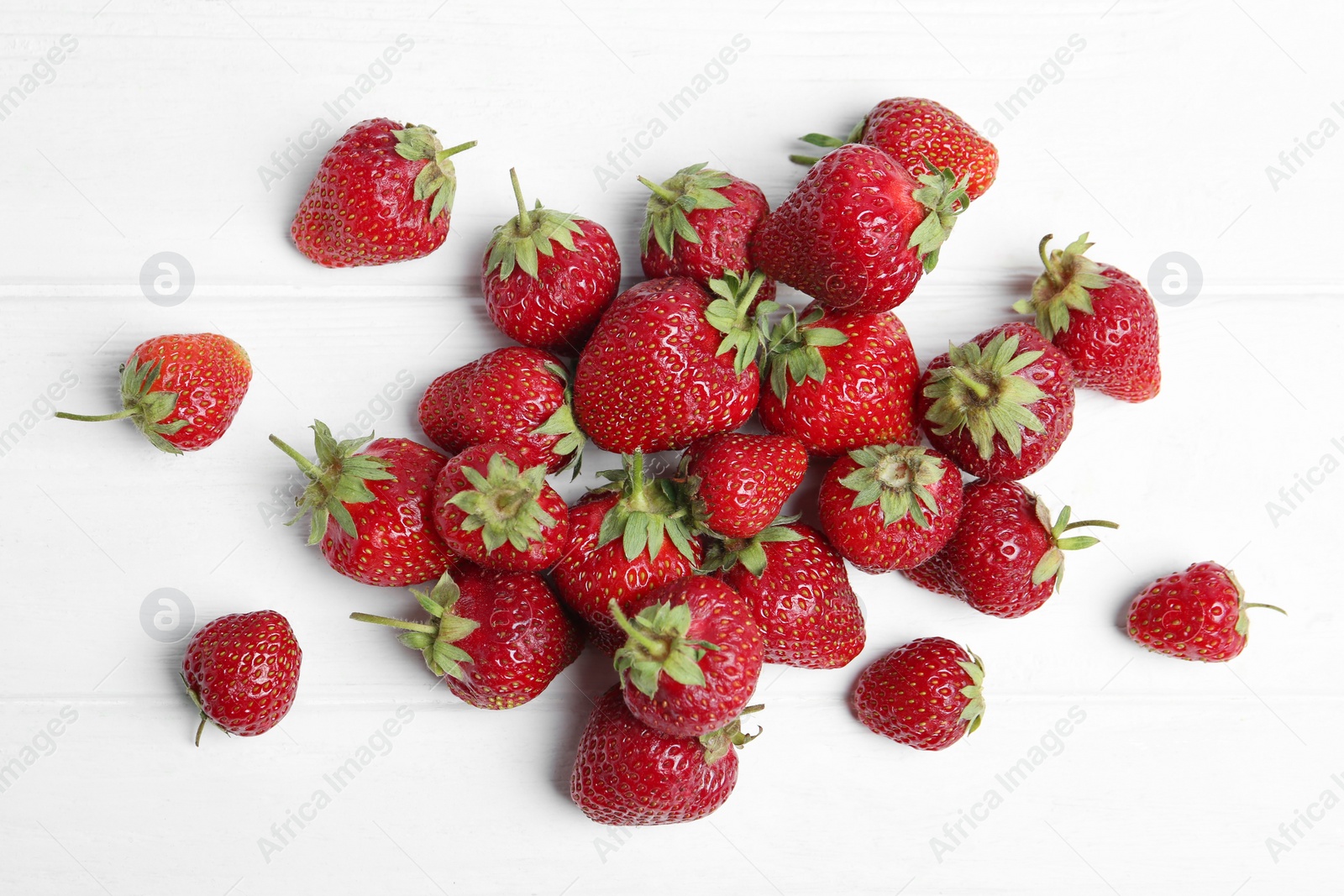 Photo of Delicious ripe strawberries on white wooden table, flat lay