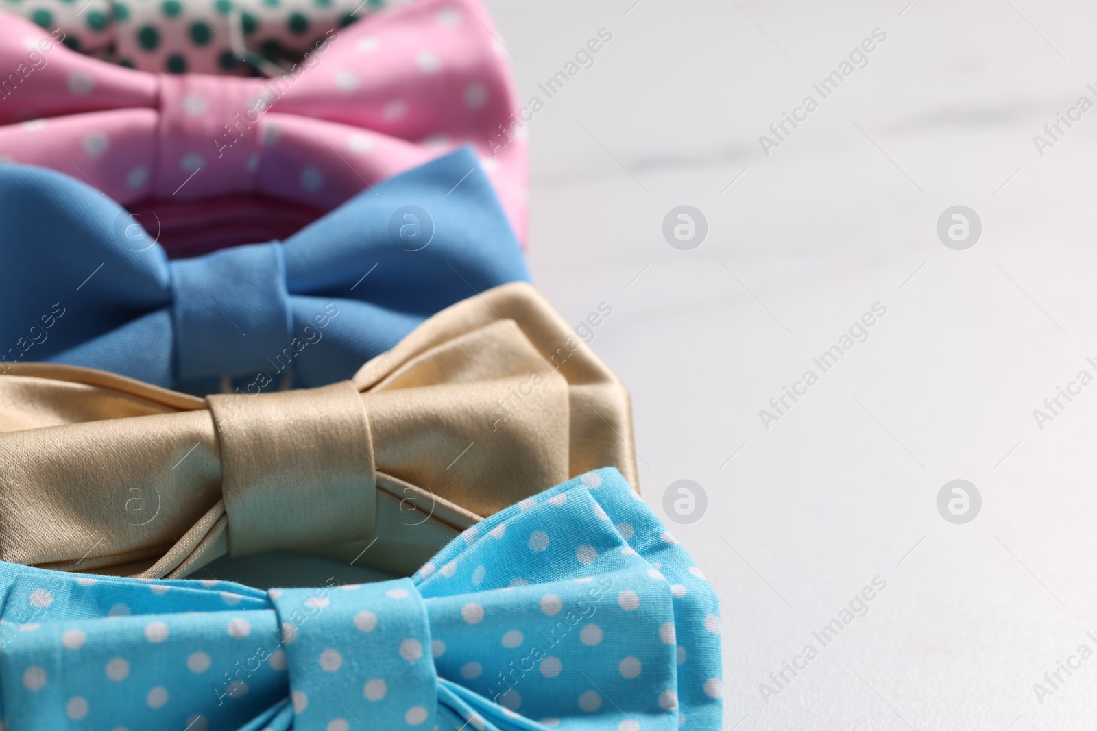 Photo of Stylish color bow ties on white background, closeup. Space for text