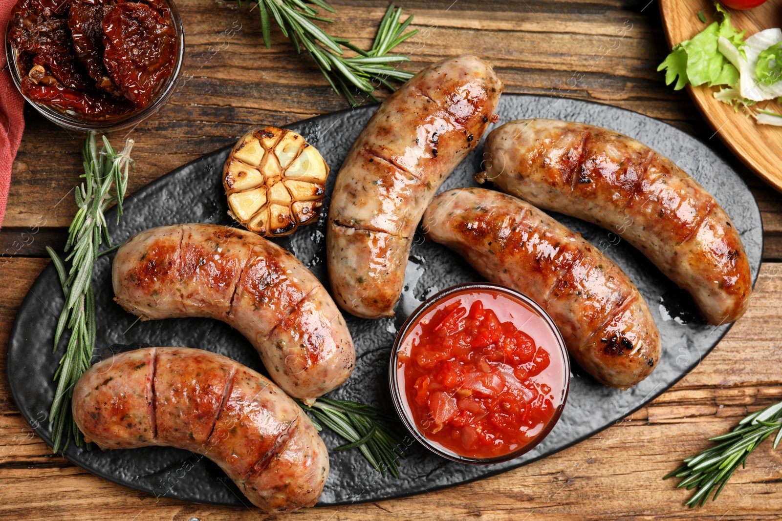 Photo of Tasty grilled sausages served on wooden table, flat lay