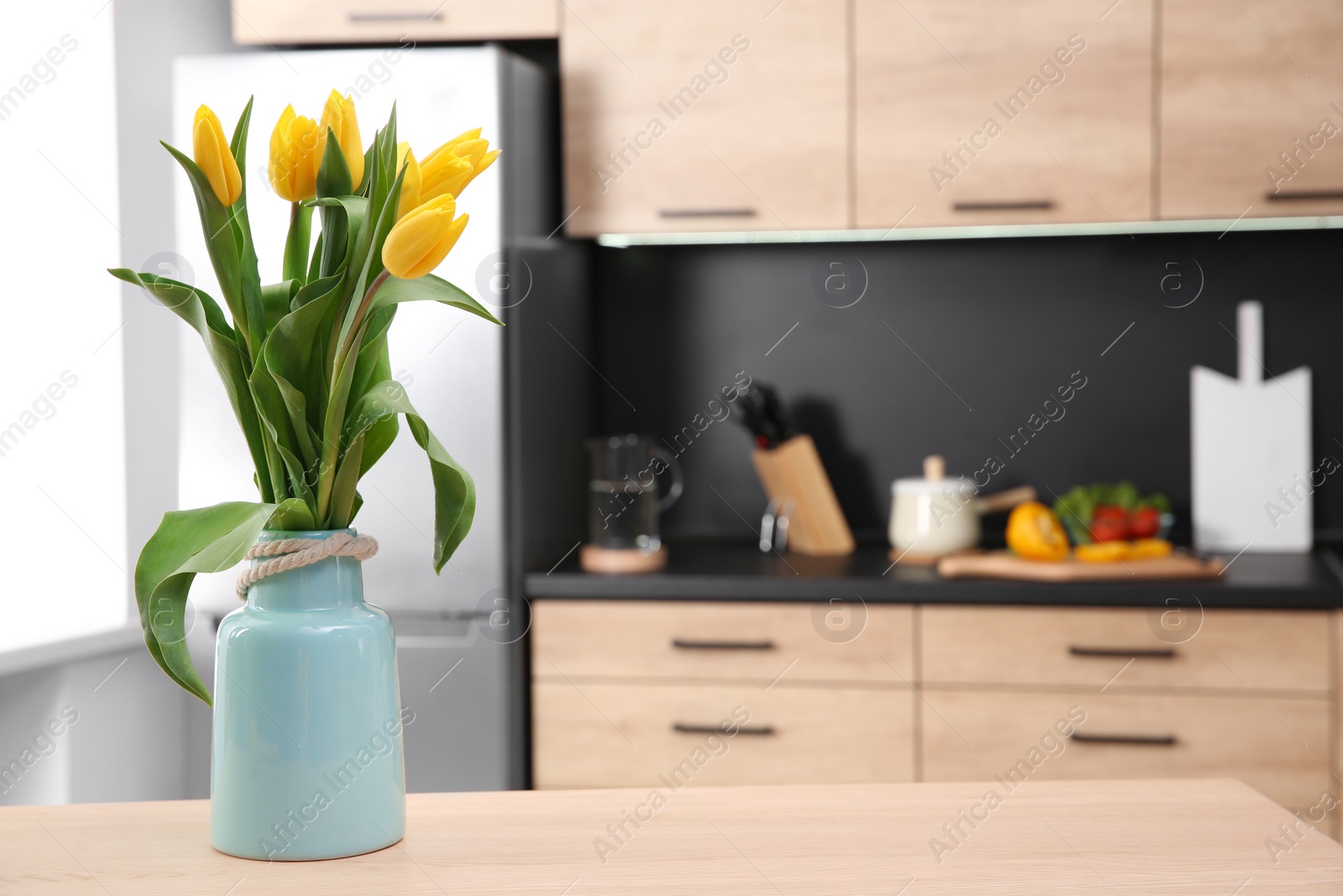 Photo of Ceramic vase with tulips on table in kitchen