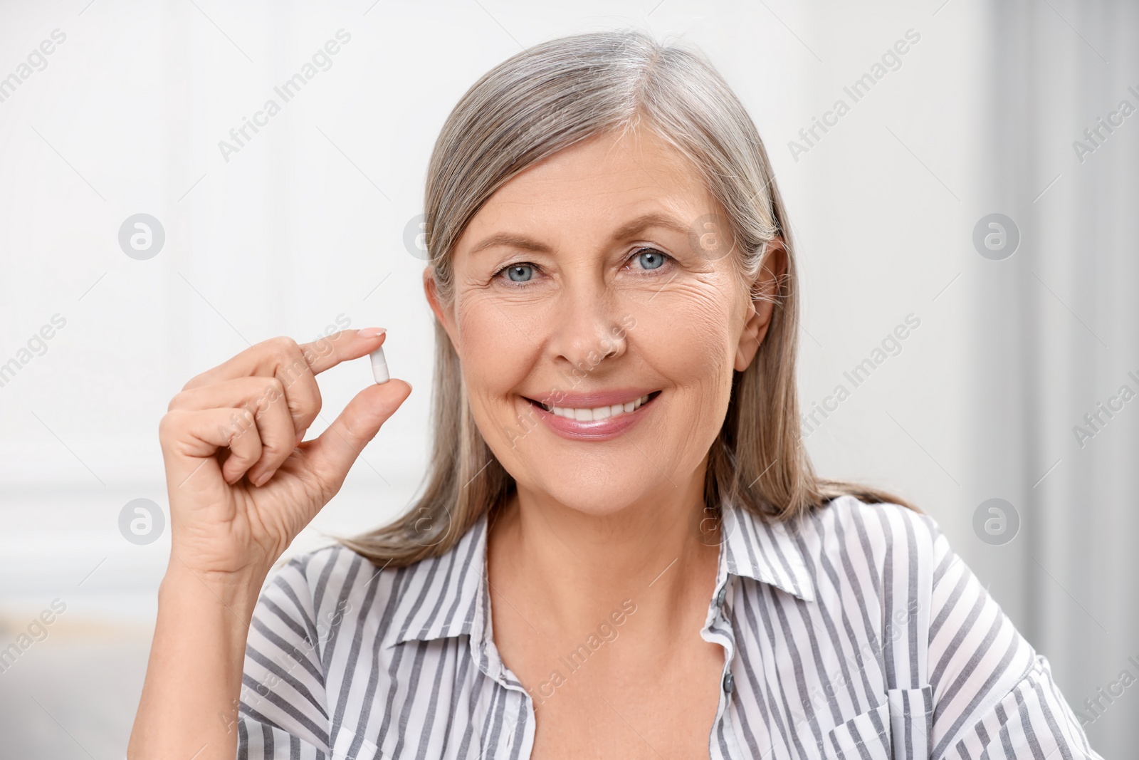 Photo of Menopause, hormone replacement therapy. Happy woman holding pill at home