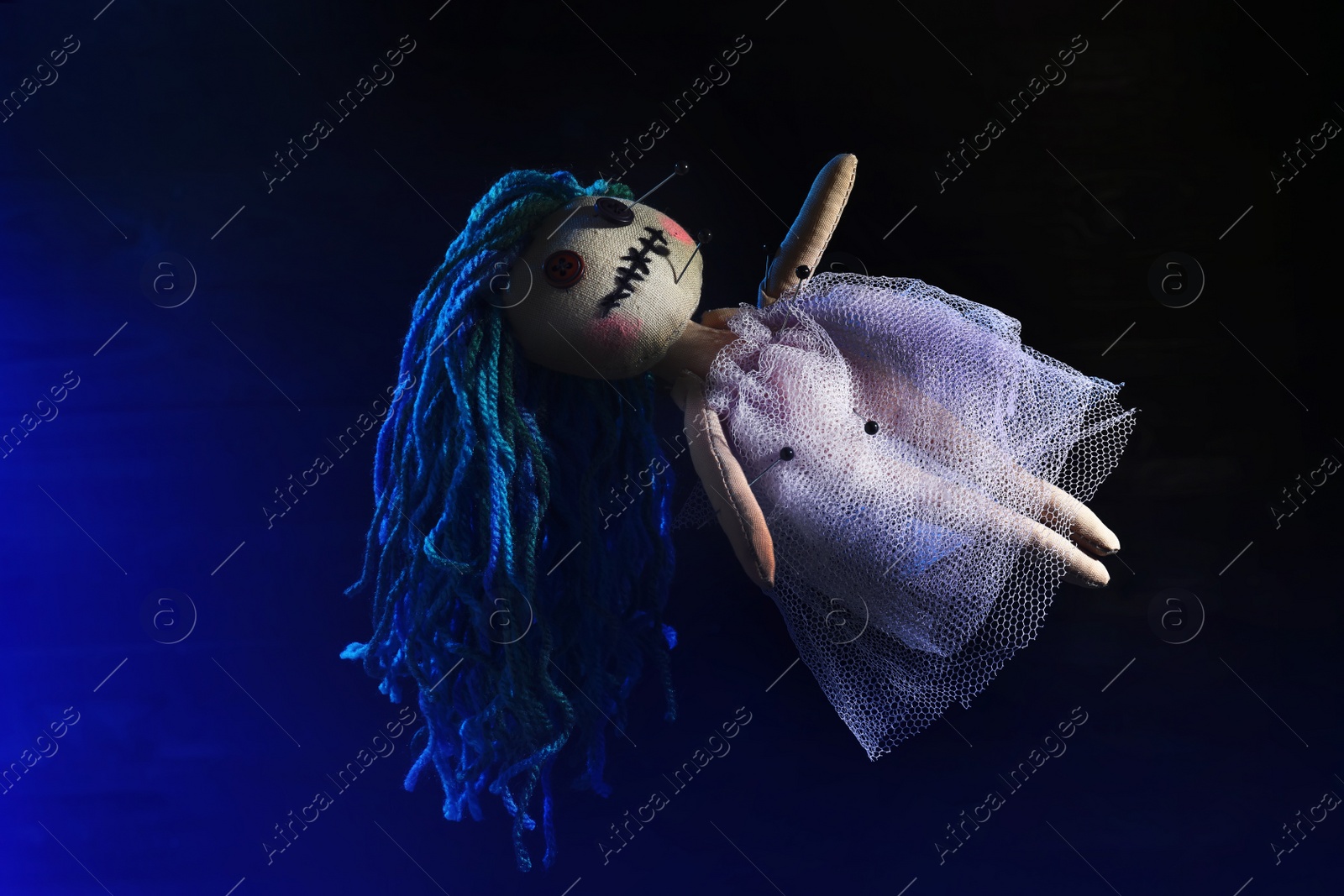 Image of Female voodoo doll with pins on dark blue background