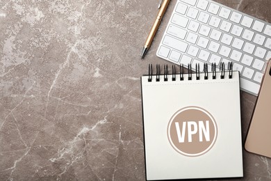 Image of Notebook with acronym VPN and space for text on brown marble table, flat lay. Secure network connection