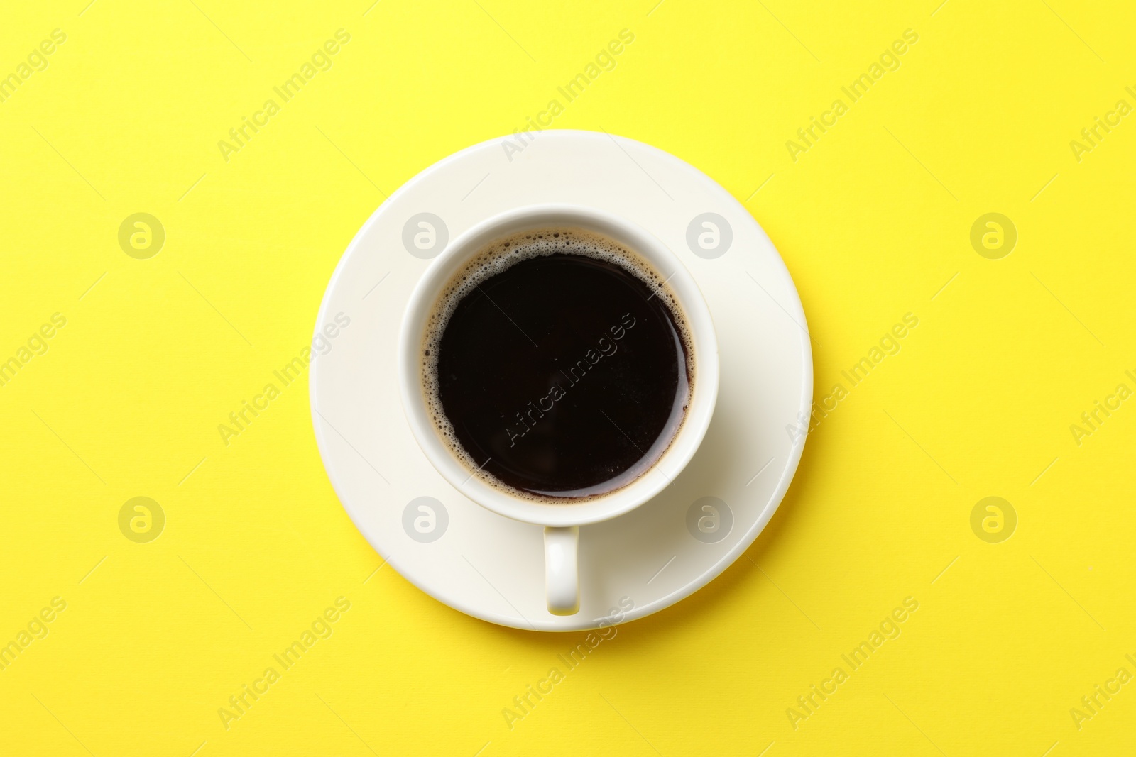 Photo of Cup of aromatic coffee on yellow background, top view