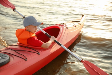 Photo of Little boy kayaking on river. Summer camp activity