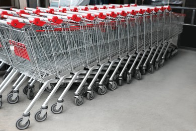Photo of Many empty metal shopping carts near supermarket outdoors