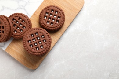 Tasty chocolate sandwich cookies with cream on light grey marble table, flat lay. Space for text