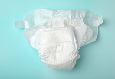 Photo of Baby diaper on turquoise background, top view