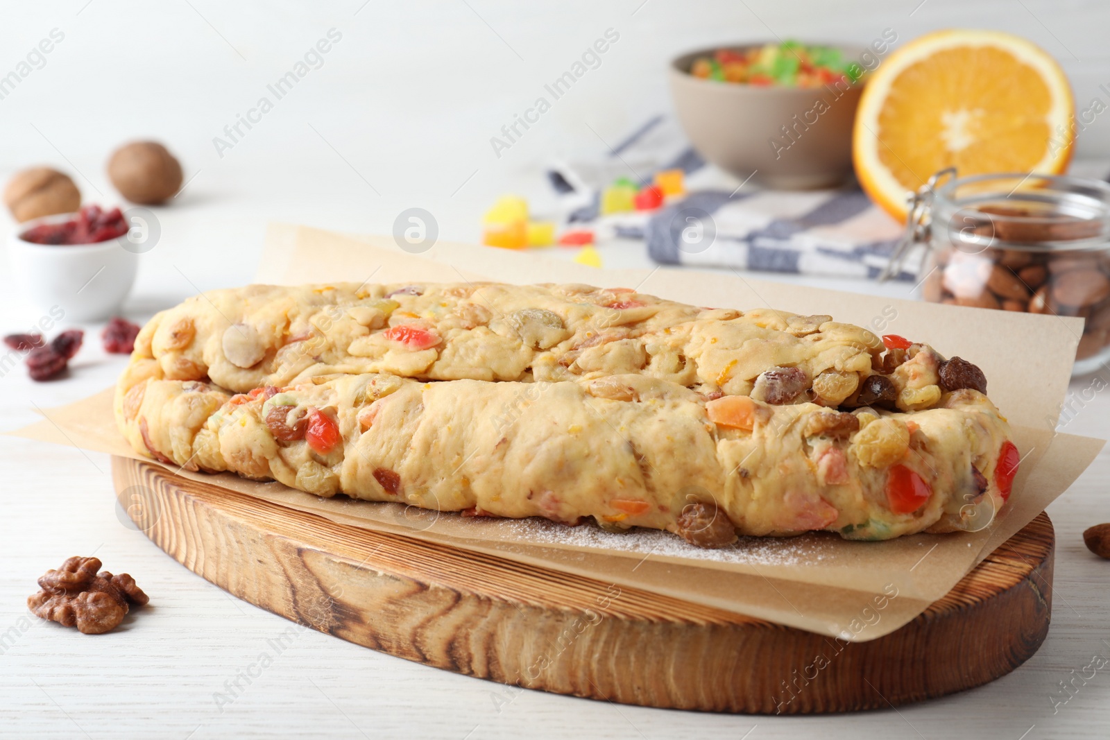 Photo of Unbaked Stollen with candied fruits and raisins on white wooden table, closeup