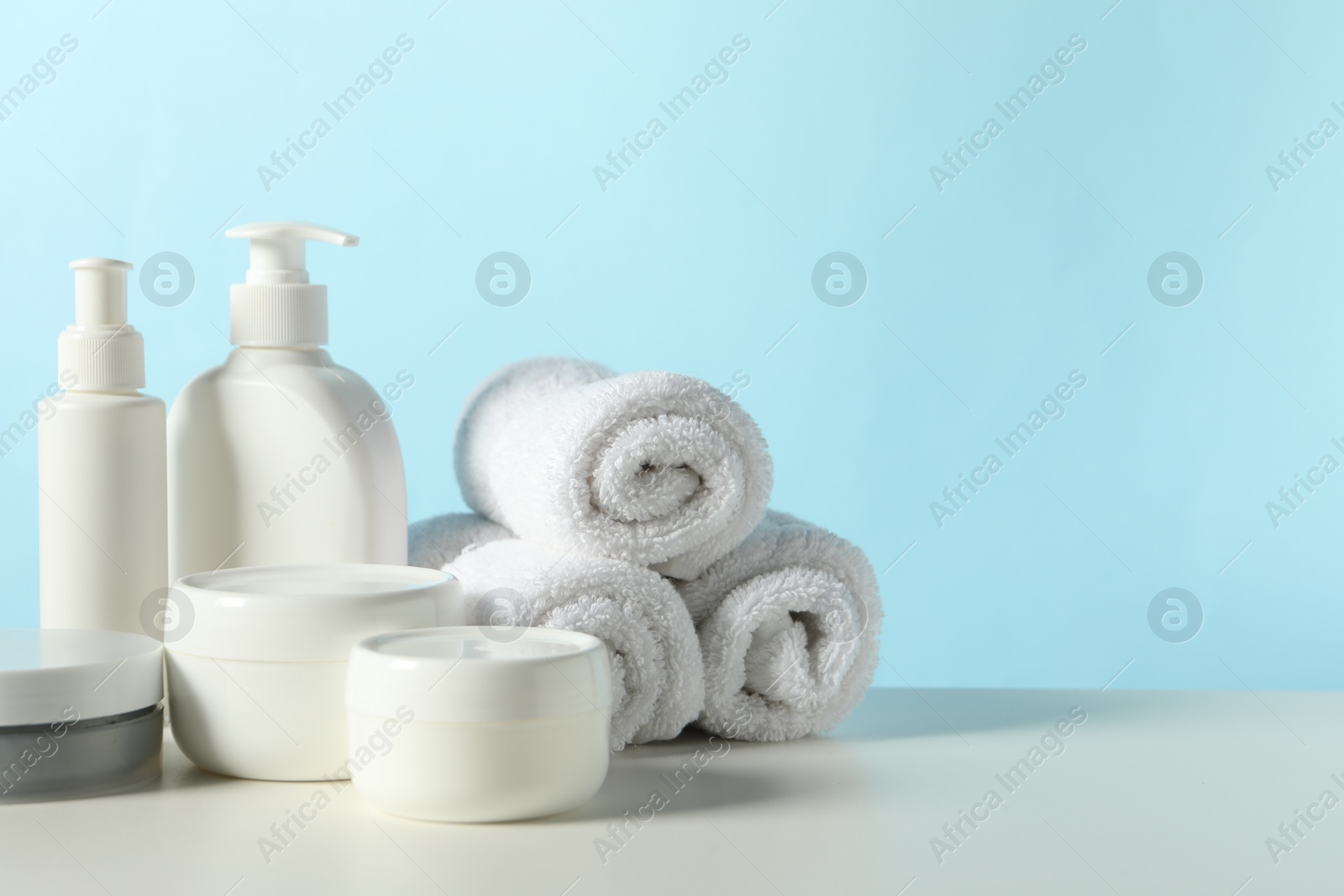 Photo of Different bath accessories on white table against light blue background. Space for text