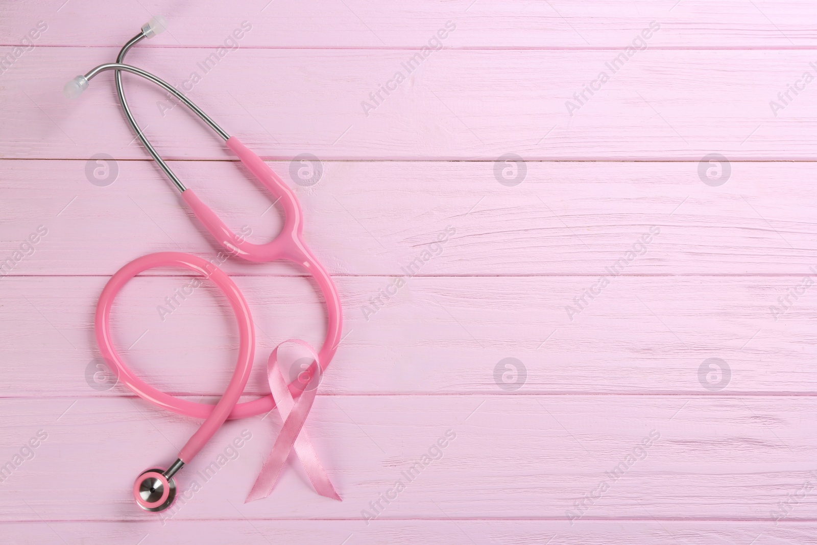 Photo of Pink ribbon and stethoscope on wooden background, flat lay with space for text. Breast cancer concept