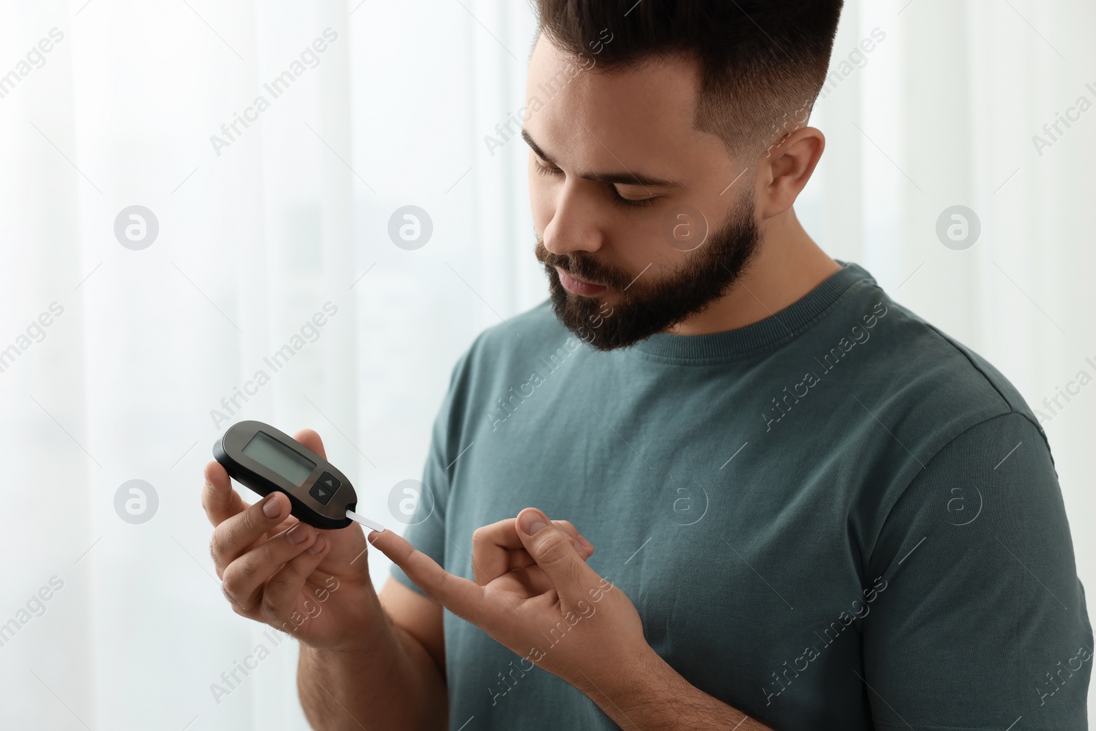 Photo of Diabetes test. Man checking blood sugar level with glucometer at home