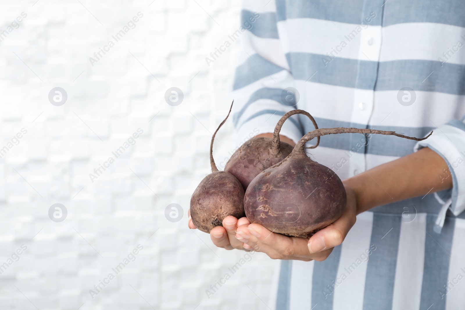 Photo of Woman holding ripe beets on light background