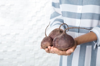 Photo of Woman holding ripe beets on light background