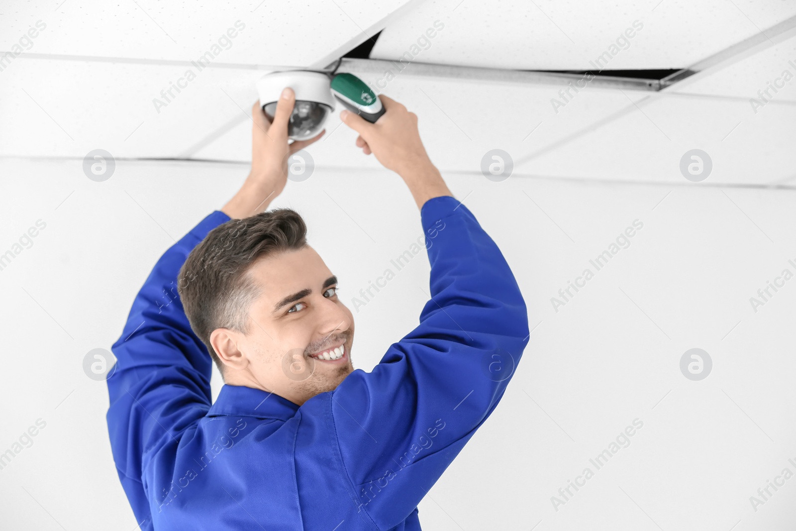 Photo of Technician installing CCTV camera on ceiling indoors