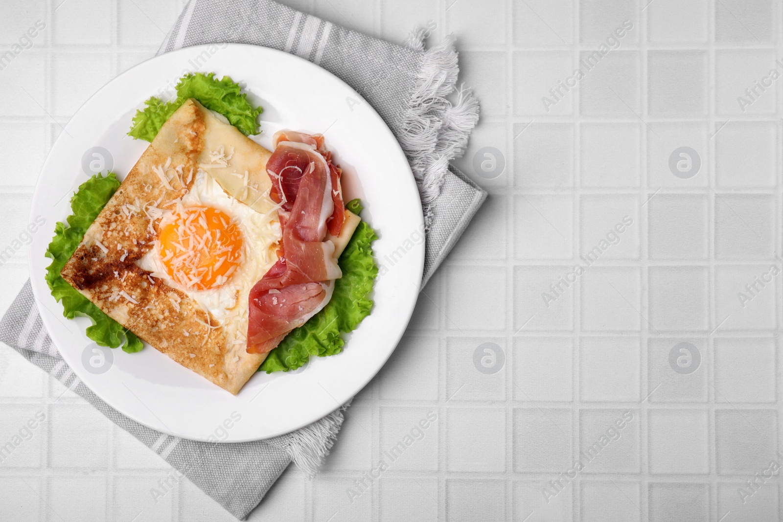 Photo of Delicious crepe with egg served on white tiled table, flat lay with space for text. Breton galette