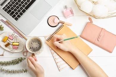Photo of Woman with notebook, cosmetics and coffee on wooden background, flat lay. Beauty blogger