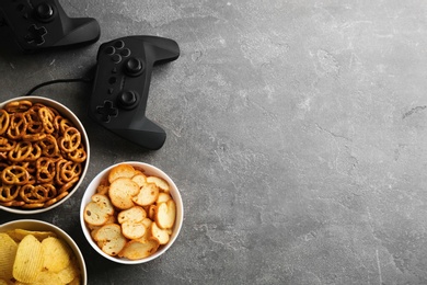 Flat lay composition with video game controller, snacks and space for text on grey background