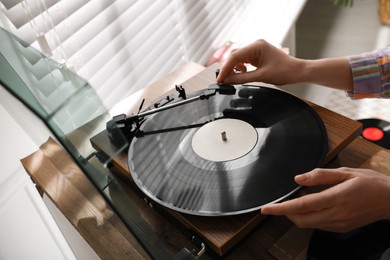 Photo of Young woman using turntable at home, closeup