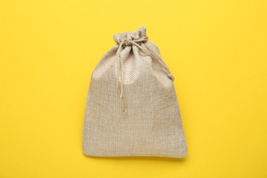 Photo of Tied burlap bag on yellow background, top view