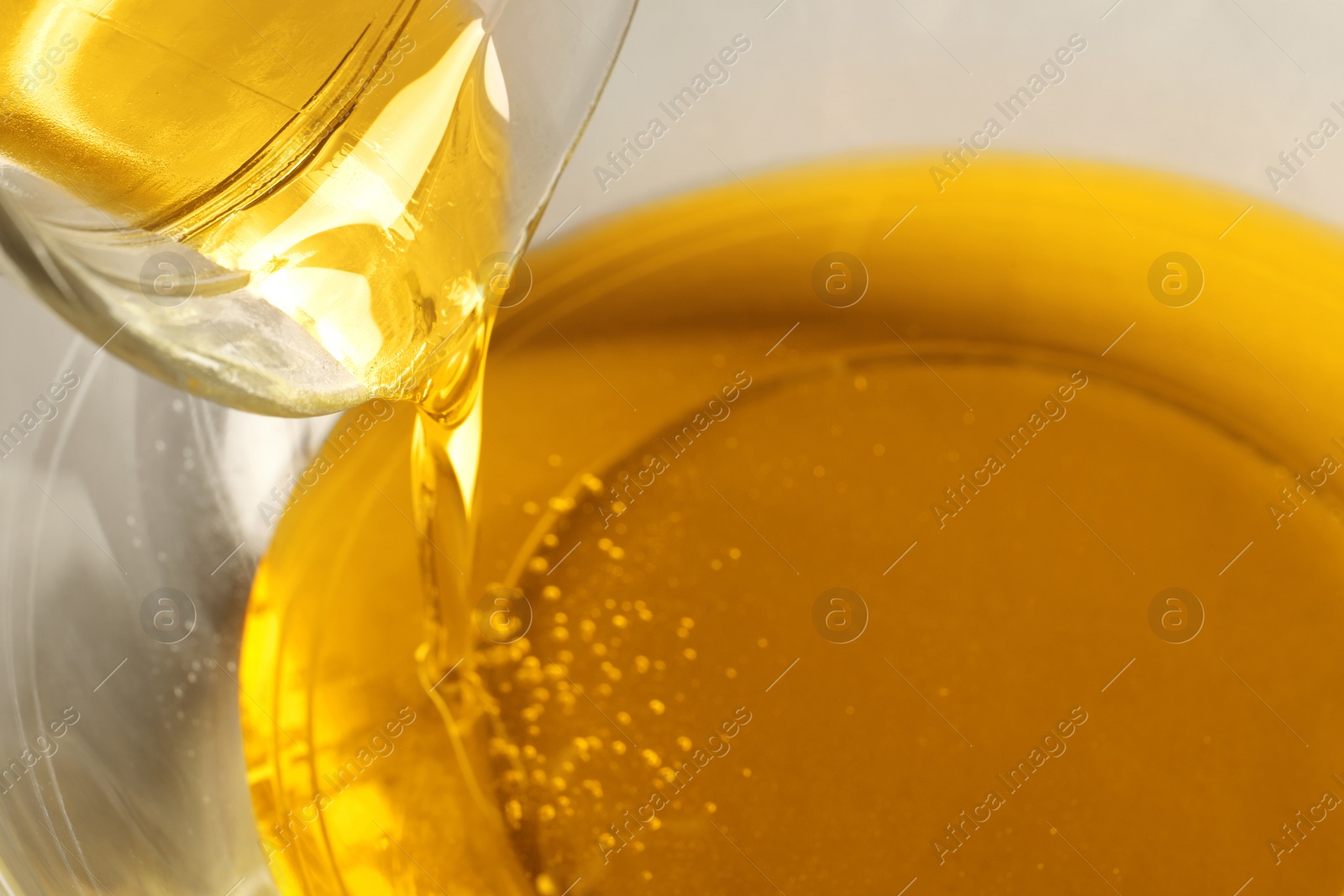 Photo of Pouring cooking oil from jug into bowl, closeup