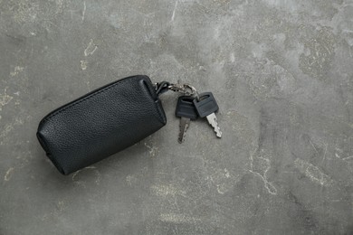 Photo of Leather case with keys on grey textured table, top view. Space for text