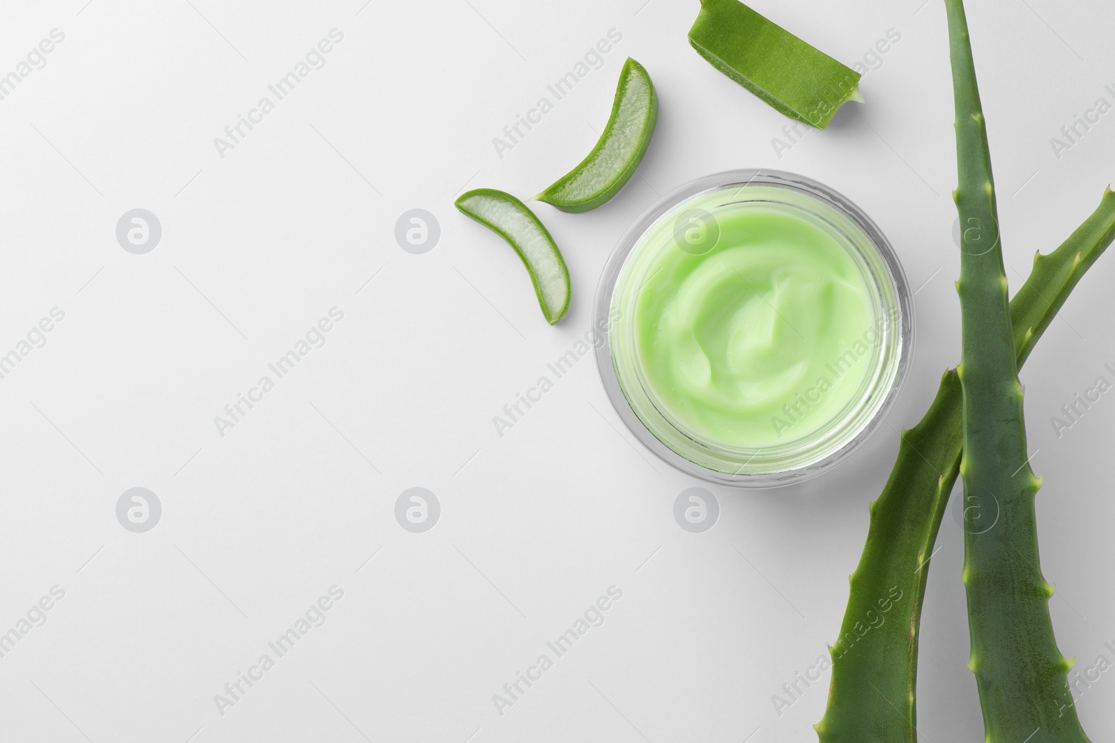 Photo of Jar of natural cream and cut aloe leaves on white background, flat lay. Space for text