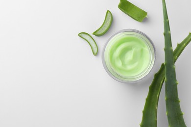 Photo of Jar of natural cream and cut aloe leaves on white background, flat lay. Space for text