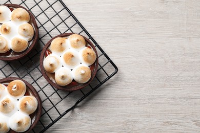 Delicious salted caramel meringue tarts on light wooden table, flat lay. Space for text