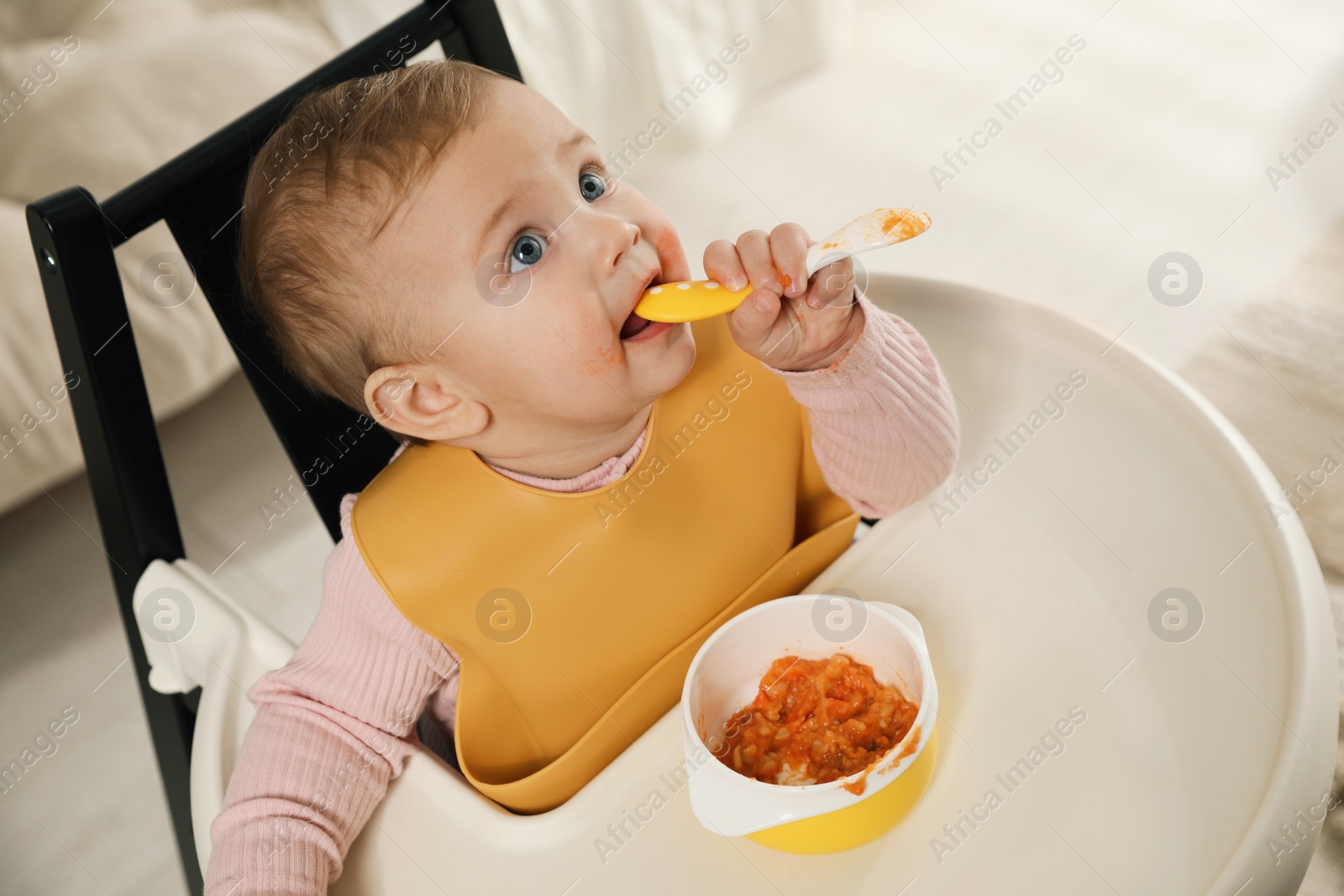 Photo of Cute little baby wearing bib while eating at home