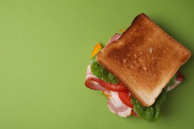 Photo of Tasty sandwich with bacon and tomato on green table, top view. Space for text