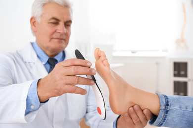 Male orthopedist fitting insole on patient's foot in clinic