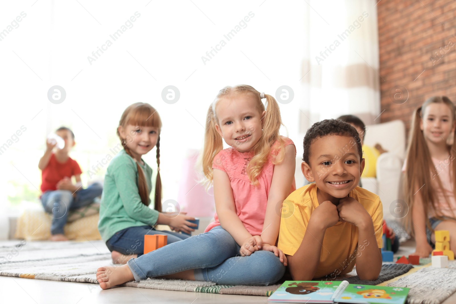 Photo of Cute little children with book and blocks indoors. Learning by playing