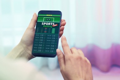 Image of Woman betting on sports using smartphone at home, closeup. Bookmaker website on display