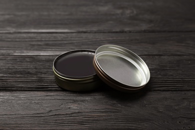 Photo of Can of black shoe polish on wooden table. Footwear care item