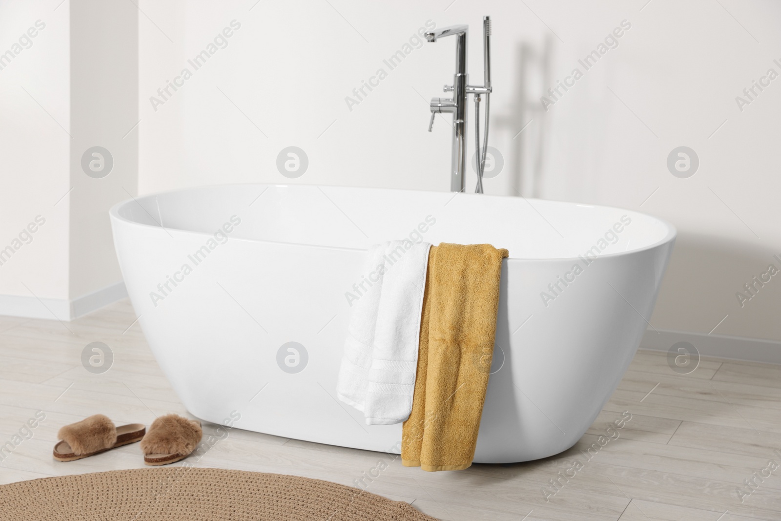 Photo of Stylish bathroom interior with ceramic tub and terry towels